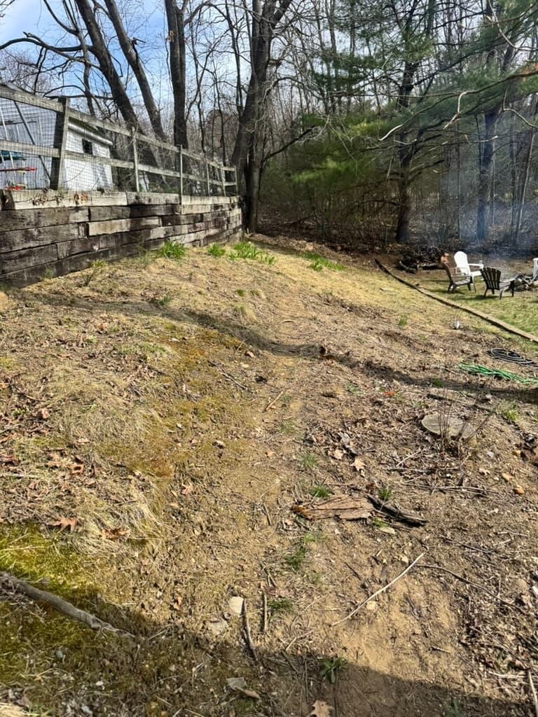 A cleared and graded hillside next to an existing retaining wall, prepped for the next project