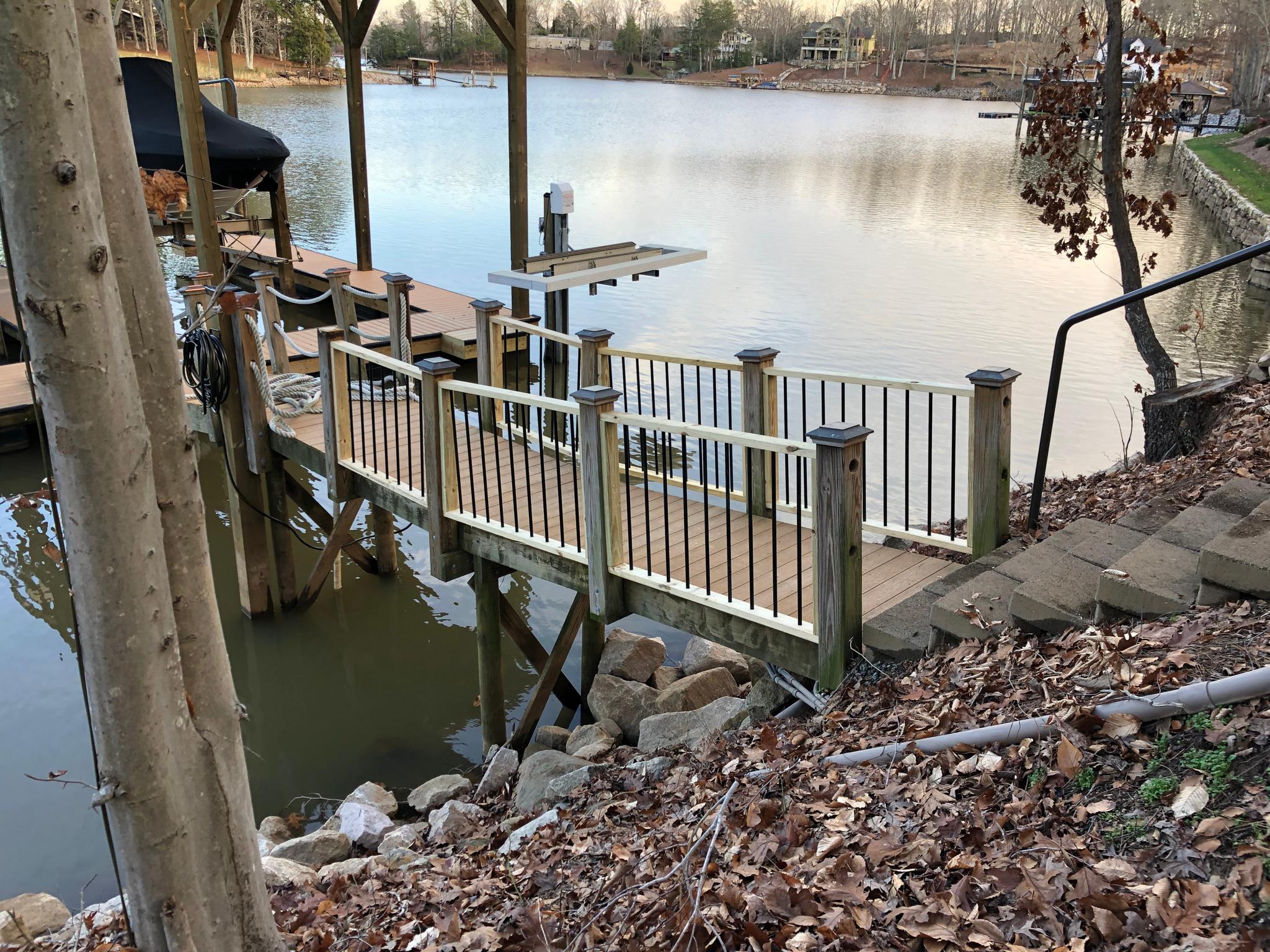 Custom wooden walkway with railings leading out over a lake, with stone steps alongside